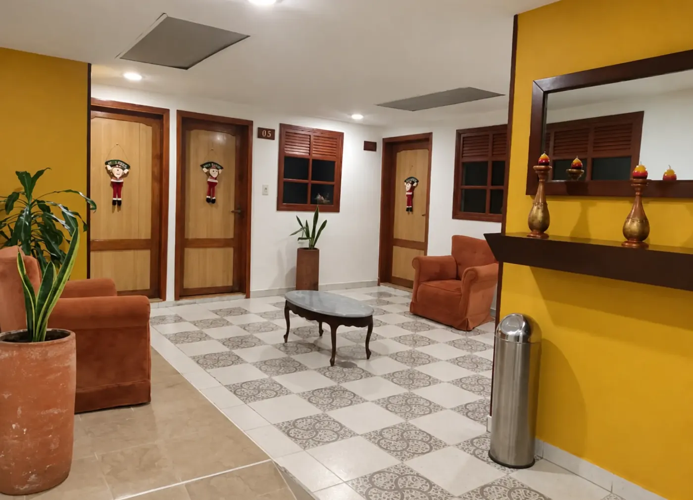 Pasillo de habitaciones con paredes amarillas, baldosas decoradas y sillones