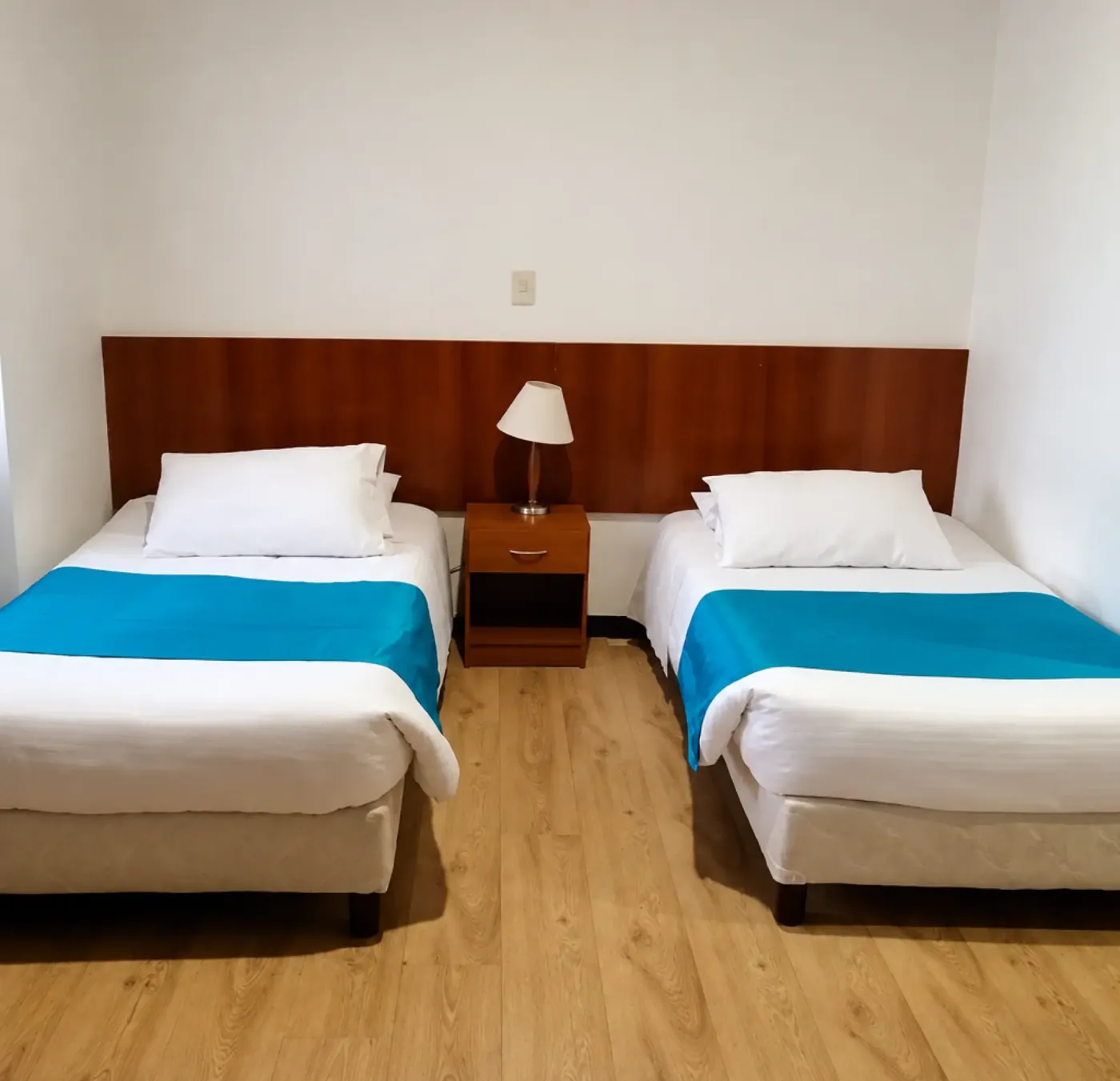 Habitación con dos camas sencillas y una lámpara de noche